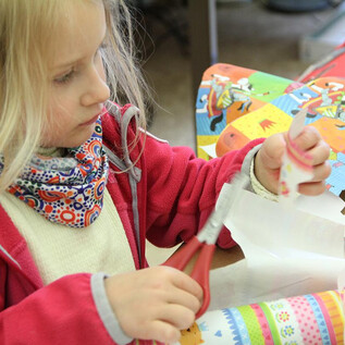 Une collection de crayons de couleur et de ciseaux dans des contenants en métal. Au premier plan, des bols orange sont visibles. | © DomQuartier