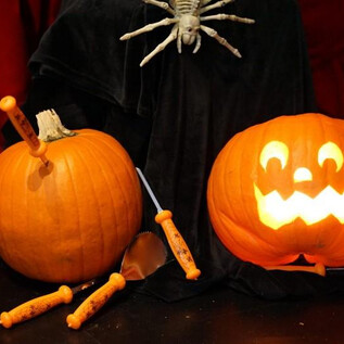 Két tök Halloween-motívumokkal áll egy asztalon. Az egyik tök világító és vidám arca van, míg a másik szerszámokkal van díszítve. | © Salzburg Museum