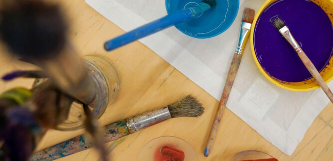 Két tök Halloween-motívumokkal áll egy asztalon. Az egyik tök világító és vidám arca van, míg a másik szerszámokkal van díszítve. | © Khan Eram/Spielzeug Museum