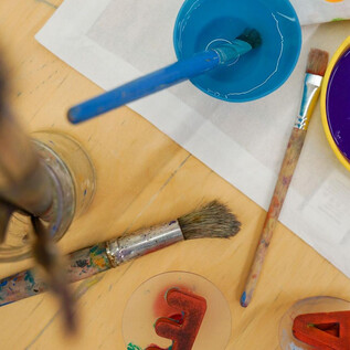 Két tök Halloween-motívumokkal áll egy asztalon. Az egyik tök világító és vidám arca van, míg a másik szerszámokkal van díszítve. | © Khan Eram/Spielzeug Museum