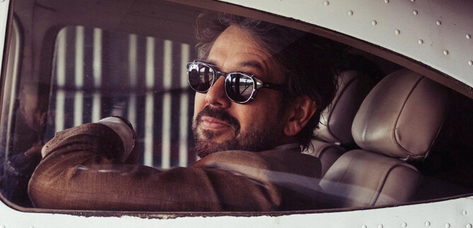 A man with sunglasses is casually sitting in an airplane. The interior is modern and well-lit. | © SKOW