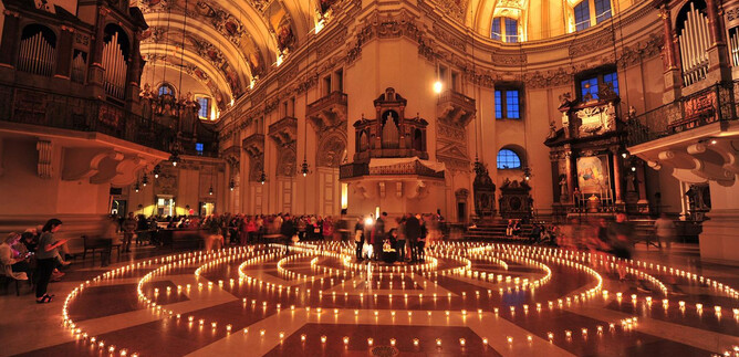 An impressive church with a large number of burning candles arranged in a spiral pattern. The high ceiling and the ornate decorations create a festive atmosphere. | © eds WEB