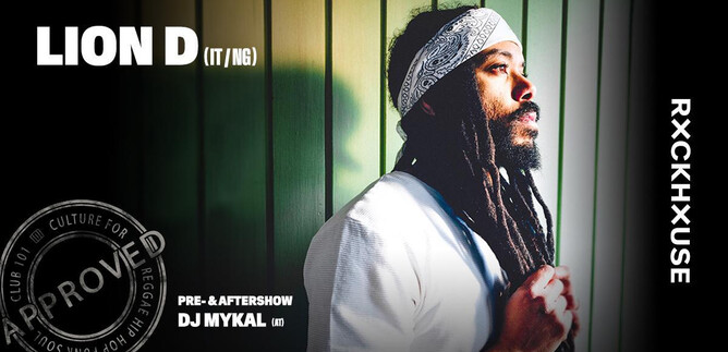 A man with long, curly hair stands in a slightly shaded area. He is wearing a white top and is looking thoughtfully to the side. | © Rockhouse Salzburg