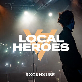 Egy élénk koncertszínpad egy zenésszel az előtérben és csillogó fényekkel a háttérben. A "Local Heroes" felirat középen helyezkedik el. | © Rockhouse Salzburg