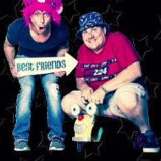 Zwei Freunde posieren fröhlich mit einem Schild "Best Friends". Sie tragen bunte Hüte und haben eine lustige, entspannte Ausstrahlung. | © Das OFF Theater Salzburg