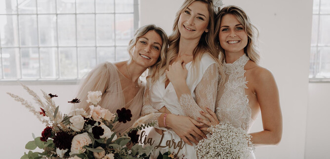 A vibrant stage performance with four artists standing in glittering outfits in front of a large heart-shaped disco ball. Colorful lights and a festive atmosphere create a cheerful mood. | © Austria Wedding