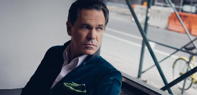 A contemplative man sits by the window and gazes outside. He is wearing an elegant suit and has a stylish demeanor. | © Anna Webber
