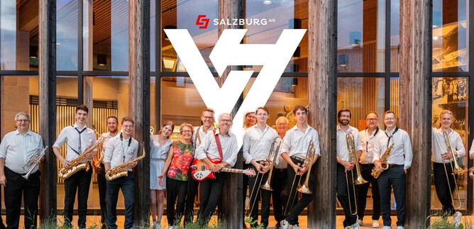 Eine Gruppe von Musikern steht vor einem modernen Gebäude mit Holzfassade. Sie halten verschiedene Musikinstrumente und lächeln in die Kamera. | © Rockhouse Salzburg
