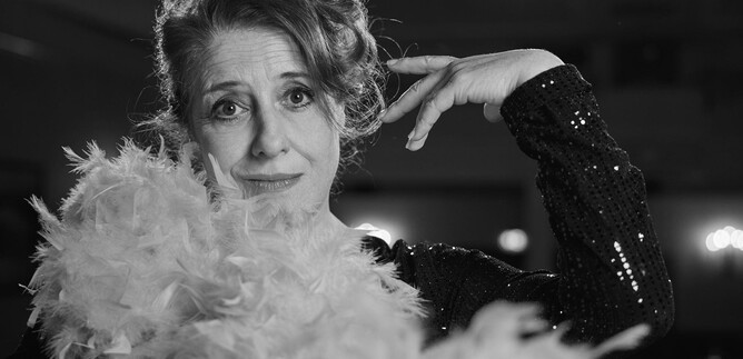 A woman with a feather boa poses elegantly. She wears a sparkling black outfit and has a charming presence. | © Martina Bogdahn