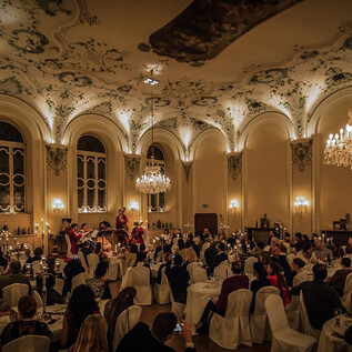 Ein eleganter Saal mit Kristalllüstern und prachtvoller Decke. Viele Gäste genießen ein festliches Dinner in festlicher Atmosphäre. | © Michael Groessinger