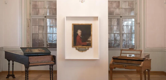 An exhibition room with two keyboard instruments and a portrait in the middle. The walls are light and the windows let in a lot of light. | © Wolfgang Lienbacher