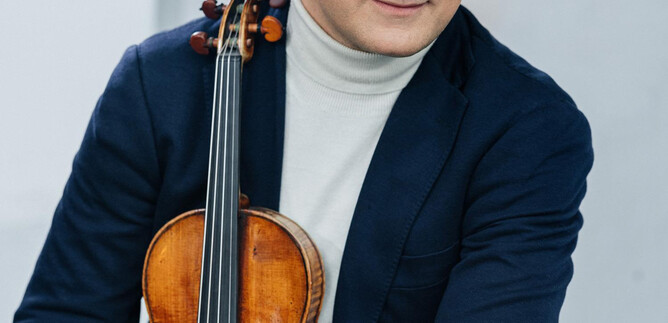 Ein Musiker sitzt mit einer Violine in der Hand. Er trägt einen eleganten Blazer und schaut freundlich in die Kamera. | © Universal Music