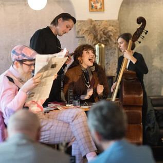A vibrant live performance in a cozy café. The singer entertains the audience while the musicians play in the background. | © Wolfgang Lienbacher