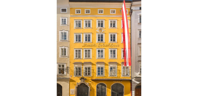 A yellow building with many windows and a striking facade. Two red flags are hanging on the side. | © ISM_Wolfgang Lienbacher