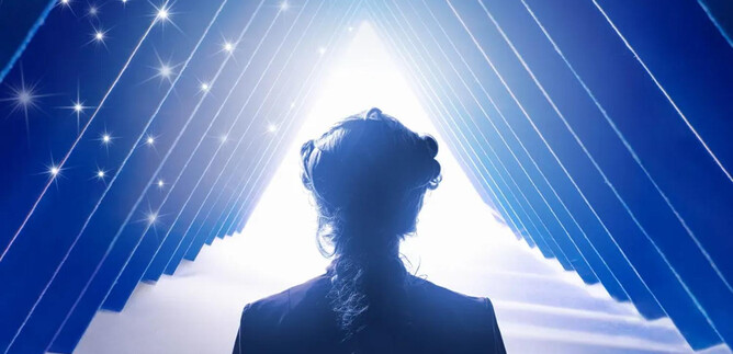 A person stands in the foreground and looks at a bright light surrounded by blue geometric shapes. The atmosphere feels mystical and inspiring. | © ISM