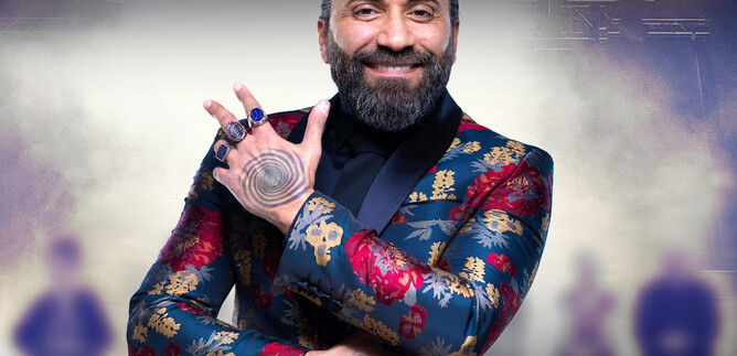 A man in a colorful, floral patterned suit smiles and makes a hand gesture. In the background, blurred silhouettes can be seen, conveying a fighting mood. | © @hypnox-akademie