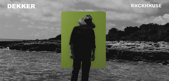 Ein Mann steht am Strand mit einem Hut und hat seinen Kopf gesenkt. Im Hintergrund sind Wellen und eine bewölkte Himmel. | © James Keane