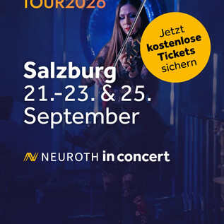 Ein Mann hält eine Geige in der Hand und lächelt. Der Hintergrund ist dunkel und schlicht. | © Neuroth