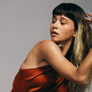A woman in a red dress poses artistically. She has long, wavy hair and an expressive gaze. | © Chris Rogl