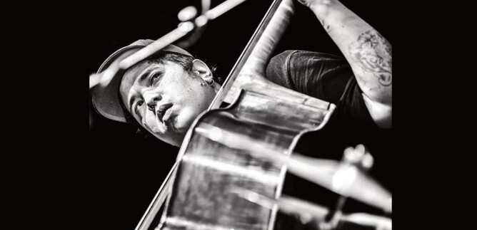 A musician passionately plays a cello on stage. He is wearing a cap and has visible tattoos. | © Jazzit