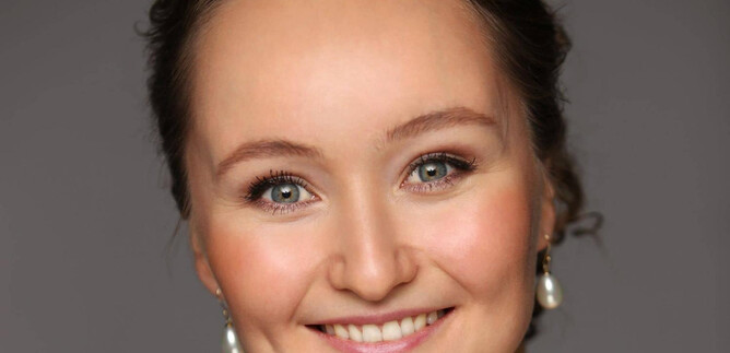 Una donna con un sorriso amichevole e occhi brillanti. Indossa orecchini eleganti e ha un'irradiamento naturale. | © Emil Matveev