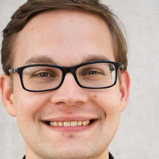A young man with glasses is smiling at the camera. The background is bright and neutral. | © www.salzburger-dom.at