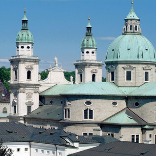 An impressive church architecture with green domes and tall towers. The clear sky complements the historical beauty of the building. | © Erzdiözse Salzburg, Foto: J. Kral