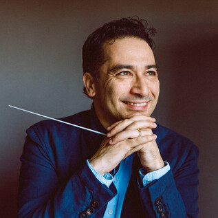 Ein lächelnder Mann mit einem Stab in der Hand sitzt nachdenklich da. Er trägt einen blauen Anzug und hat einen freundlichen Ausdruck. | © Julia Sellmann