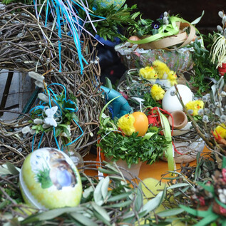 Colorful Easter arrangements with eggs, artificial chicks, and fresh plants. The table is festively decorated with branches and flowers. | © Salzburger Freilichtmuseum