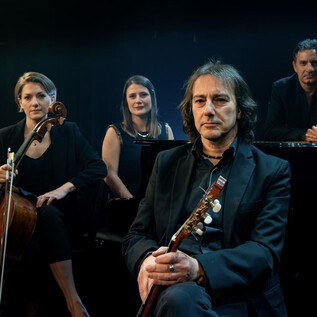 Eine Gruppe von vier Musikern posiert auf der Bühne. Sie spielen verschiedene Instrumente und strahlen eine kreative Atmosphäre aus. | © Pippo Pollina | Konzertphotograph