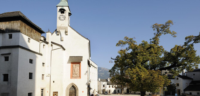 A quiet place with a white church and a large tree. The sky is clear and blue, creating a peaceful atmosphere. | © Salzburger Burgen und Schlösser