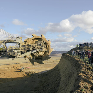 Tři dopravní značky stojí v zasněžené krajině. Atmosféra je šedá a mlhavá, s klidným potokem v pozadí. | © Nolting