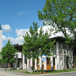 Eine moderne Kirche mit einem spitzen Turm und Glasdach. Umgeben von Bäumen und einem klaren Himmel. | © Pfarre St. Paul