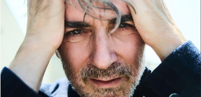 A man with gray hair holds his hands to his face. He looks thoughtful and tense. | © Julian Baumann