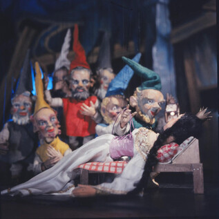 Eine Gruppe von farbenfrohen Puppen steht um eine schlafende Figur. Die Szene wirkt märchenhaft und einladend. | © Salzburger Marionettentheater