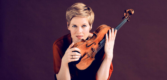 A woman holds a violin and looks directly at the camera. The background is in soft shades of brown. | © Felix Broede