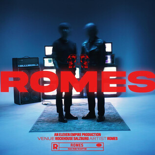 Két sziluett alak áll több képernyő előtt egy kék szobában. A "ROMES" felirat piros betűkkel kiemelve. | © Rockhouse Salzburg