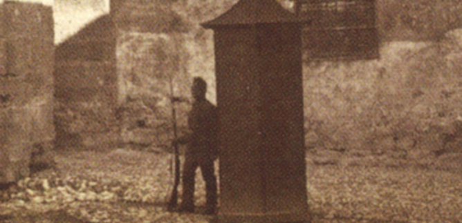 A historic kitchen with old cooking utensils and a stone fireplace. The floor is made of large stones, and there are various pots and jugs. | © Festung Hohensalzburg
