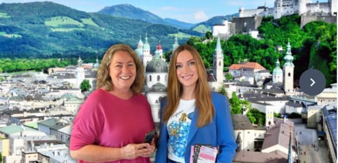 Two women stand in front of a picturesque city view with mountains in the background. The city has historic buildings and landmarks. | © Sabine Rath