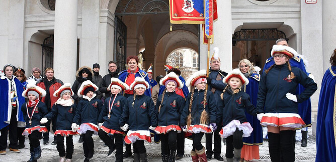 A group of children in traditional costumes stands on a street at an event. In the background, spectators and decorations can be seen. | © 1. Salzburger Faschingsgilde