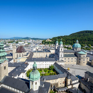 Impozantní výhled na město Salzburg s historickými budovami a zelenými kopci. Jasná modrá obloha dotváří malebný obraz. | © Tourismus Salzburg
