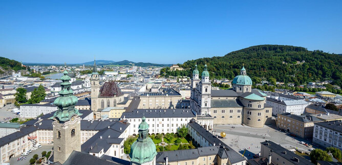 An impressive view of the city of Salzburg with historic buildings and green hills. The clear blue sky completes the picturesque image. | © Tourismus Salzburg