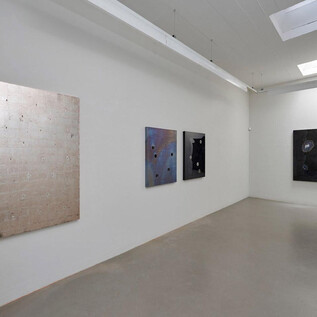 Moderní umělecká galerie se čtyřmi velkoplošnými obrazy na zdi. Obrazy se liší v barvě a textuře, na šedé podlaze. | © Galerie Frey