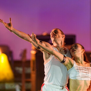 Un par de bailarines realiza una actuación impresionante en un escenario. Se mueven elegantemente a la luz de los focos. | © J. Bollwein