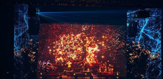 An impressive concert with vibrant lights and a large music group on stage. The background features a fascinating visual spectacle. | © SHOW FACTORY Entertainment GmbH