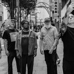 Skupina pěti mužů stojí na městské ulici. Dívají se různými směry, zatímco jeden z nich dělá selfie. | © Yusuke Nagata