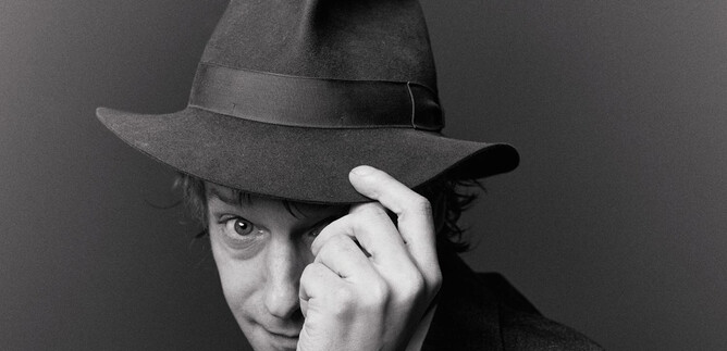 A man is wearing a hat and is smiling to the side. The shot is in black and white. | © Susanne Hassler-Smith