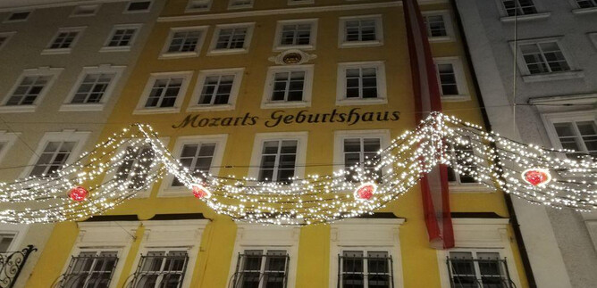 A historic building known as Mozart's birthplace shines at night. The facade is adorned with festive lights and decorations. | © ISM