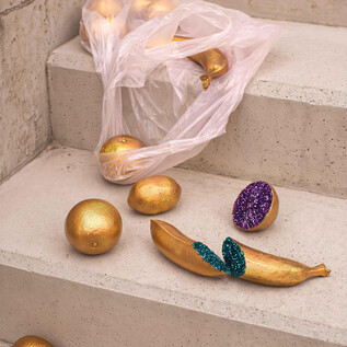 Eine ungewöhnliche Ansicht von Goldkugeln und einer bunten Banane, die auf einer Treppe verteilt sind. Eine durchsichtige Plastiktüte liegt ebenfalls auf den Stufen. | ©  Schauspielhaus Salzburg