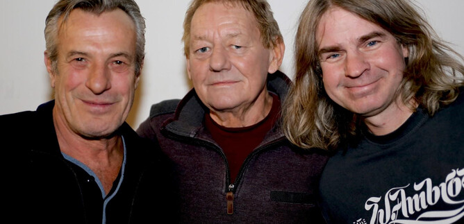 A group of three men stands together and smiles at the camera. They appear friendly and relaxed. | © Tony Schönhofer